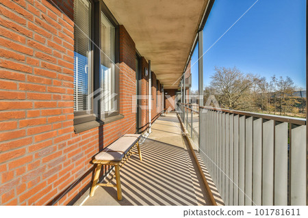 a balcony with a bench on the left side and trees in the back ground to the right, blue sky above 101781611