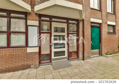 a brick building with a green door in the front and two windows on either side of the building, one is closed 101781626