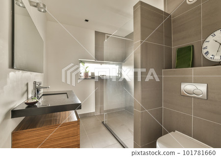 a bathroom with a clock on the wall above it and a wooden vanity next to the toilet in the corner a bathroom with a clock on the wall above it and a wooden vanity next to the toilet in the corner 101781660