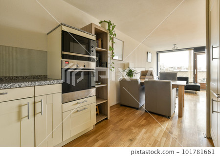 a kitchen and living room in an apartment with wood flooring, white cabinets and black appliances on the wall a kitchen and living room in an apartment with wood flooring, white cabinets and black appliances on the wall 101781661