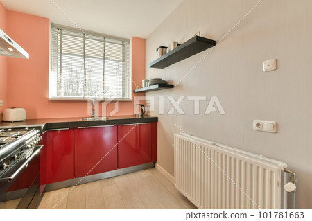 a modern kitchen with red cabinets and black appliances on the countertop, along with white radiaing walls a modern kitchen with red cabinets and black appliances on the countertop, along with white radiaing walls 101781663