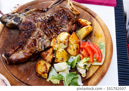 Roasted pork steak with bone with potatoes and vegetables Roasted pork steak with bone with potatoes and vegetables 101782007