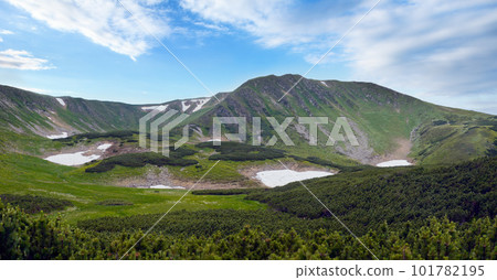 Mountain panorama view with juniper forest and snow remains on ridge in distance. Mountain panorama view with juniper forest and snow remains on ridge in distance. 101782195