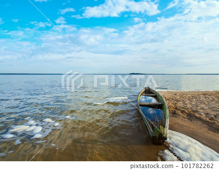 Old flooding boat on summer lake shore Old flooding boat on summer lake shore 101782262