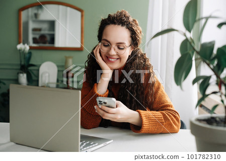 Young happy smiling pretty woman holding smartphone using cellphone modern technology, looking at 101782310