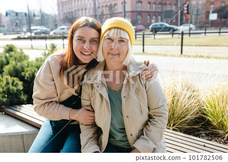 Happy friends holding each other. Happy loving older mature mother and grown millennial daughter laughing embracing, caring young woman embracing senior middle aged mom spending time together 101782506