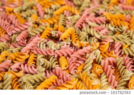 Rice vegetable pasta in the form of spirals, top view. Healthy rice pasta with tomatoes, selenera, carrots and beets 101782563