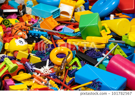 An abundance of toys in the children's room, a lot of plastic multi-colored parts from designers, spare parts for toys, figurines and cubes. An abundance of toys in the children's room, a lot of plastic multi-colored parts from designers, spare parts for toys, figurines and cubes. 101782567