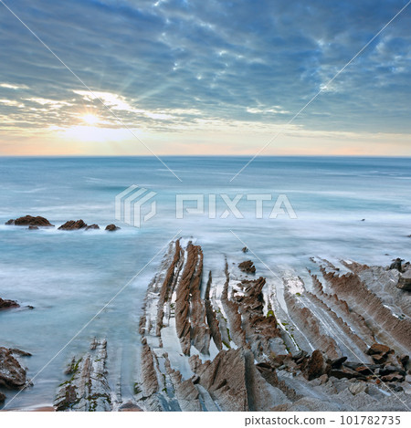 Twilight ocean coast with ribbed stratiform rock formations. (Atlantic Ocean, Spain). 101782735