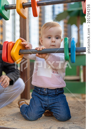 Cute baby girl Playing on Playground. Toddler playing with colored rings on playground 101784256