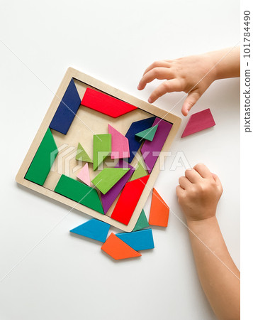 childs hand collects multicolored wooden mosaic on white background. childs hand collects multicolored wooden mosaic on white background. 101784490