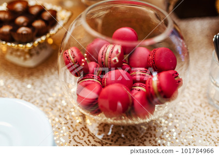 Colorful macarons stand in round transparent weight as part of candy bar sweet table. French macaroons. Candy bar. 101784966