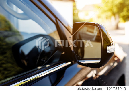 The rear view mirror on modern car on a black car. Rear view mirror car on the road. Close-up of Road safety while driving. 101785043
