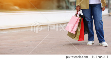 Cropped of unrecognisable woman with colourful shopping bags on urban shopping mall background. Purchases, black friday, discounts, sale concept. Online shopping concept, Seasonal Sales. copy space Cropped of unrecognisable woman with colourful shopping bags on urban shopping mall background. Purchases, black friday, discounts, sale concept. Online shopping concept, Seasonal Sales. copy space 101785091