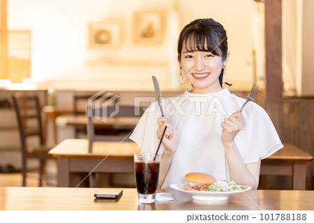 Young woman eating hamburger with fork and knife in cafe for lunch 101788188