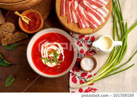 Traditional Ukrainian towel along with garlic, bread and salt. Traditional Ukrainian borsht, red vegetable soup or borscht with smetana on wooden background. Slavic dish with cabbage, beets, tomatoes 101789189