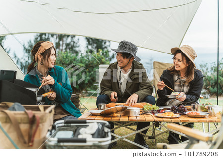 Asian couple camper and friend woman cooking at campsite in autumn winter Asian couple camper and friend woman cooking at campsite in autumn winter 101789208