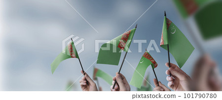 A group of people holding small flags of the Turkmenistan in their hands A group of people holding small flags of the Turkmenistan in their hands 101790780