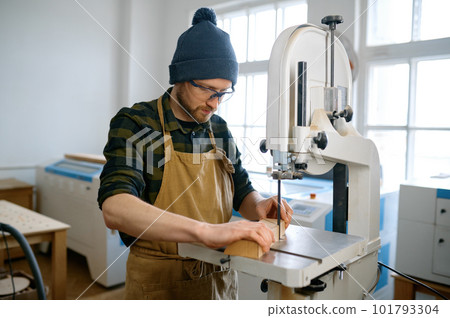 Carpenter using band saw to cut plywood, closeup shot with selective focus 101793304