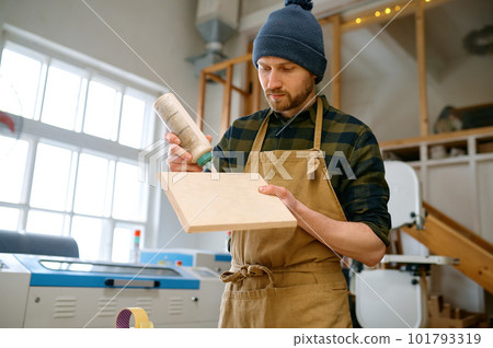 Portrait of experienced man carpentry worker applying glue on board Portrait of experienced man carpentry worker applying glue on board 101793319