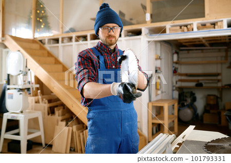 Man carpenter preparing round saw blade for woodworking at workshop 101793331