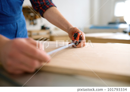 Closeup male hand measuring wooden board making furniture wooden blank Closeup male hand measuring wooden board making furniture wooden blank 101793334
