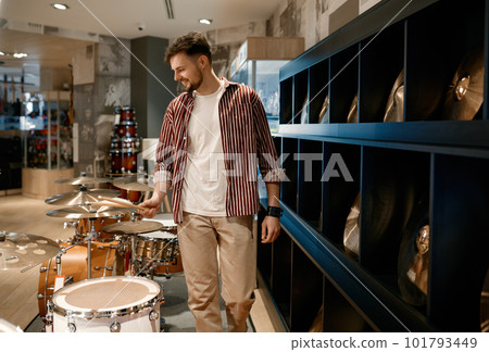 Young man buyer choosing drums at modern music shop 101793449