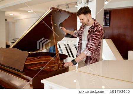 Man buyer looking on tuning keys inside grand piano under lid 101793460