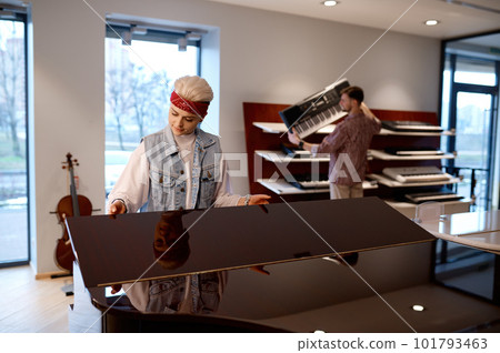 Young family couple choosing musical instrument in professional shop Young family couple choosing musical instrument in professional shop 101793463