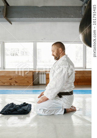 Aikido master sitting on floor and looking at folded black hakama 101793485
