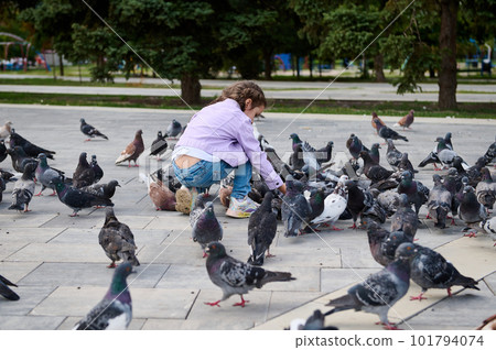 Little child girl 5 years old, feeding rock pigeons in the park square. The concept of installing of love, care and compassion for wild animals leaving in the street from childhood. People and nature 101794074