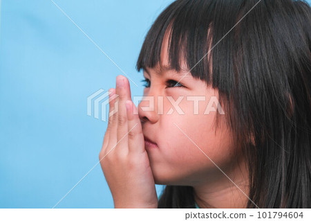 Little asian girl covering her mouth to smell the bad breath. Child girl checking breath with her hands. Oral health problems or dental care concept. 101794604