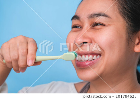 Happy Asian woman taking care of her teeth and holding a toothbrush. Young lady brushing her teeth. dental care and oral hygiene concept. Happy Asian woman taking care of her teeth and holding a toothbrush. Young lady brushing her teeth. dental care and oral hygiene concept. 101794625
