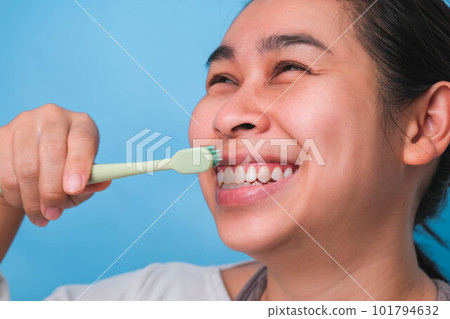 Happy Asian woman taking care of her teeth and holding a toothbrush. Young lady brushing her teeth. dental care and oral hygiene concept. Happy Asian woman taking care of her teeth and holding a toothbrush. Young lady brushing her teeth. dental care and oral hygiene concept. 101794632