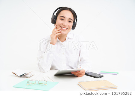 People and workplace. Smiling asian woman sits in office, student listening music in headphones and holding digital tablet, white background 101795292