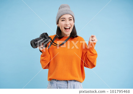 Stylish asian girl with digital camera, taking pictures. Woman photographer smiling, standing over blue background Stylish asian girl with digital camera, taking pictures. Woman photographer smiling, standing over blue background 101795468
