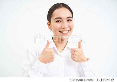 Portrait of asian businesswoman shows thumbs up, approves smth, recommends company, stands over white background 101796036