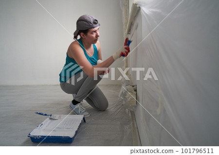Woman paints the wall with a roller Woman paints the wall with a roller 101796511