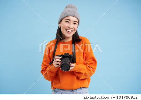 Stylish asian girl with digital camera, taking pictures. Woman photographer smiling, standing over blue background Stylish asian girl with digital camera, taking pictures. Woman photographer smiling, standing over blue background 101796912