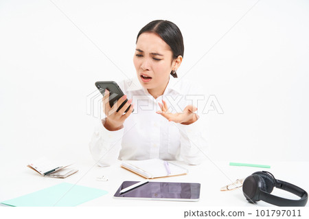 Angry lady boss, businesswoman looks frustrated, talks on mobile phone, has an argument during conversation on cellphone, sits in her office, white background 101797011