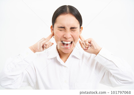 Annoyed young asian corporate worker, lady screams and shuts her ears with fingers, stands frustrated against white studio background Annoyed young asian corporate worker, lady screams and shuts her ears with fingers, stands frustrated against white studio background 101797068