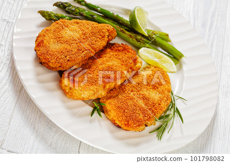 breaded chicken breasts with asparagus and lime 101798082
