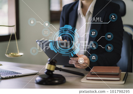 Judge in a courtroom using laptop and tablet with AML anti money laundering icon on virtual screen. 101798295