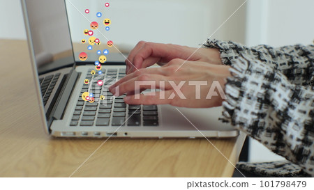 Woman uses laptop computer, types chat messages. 3D emoji, meme icons flying out of device. 101798479