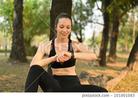 Beautiful fitness woman checking fitness results or heart rate on smartwatch, resting after workout session Beautiful fitness woman checking fitness results or heart rate on smartwatch, resting after workout session 101801083