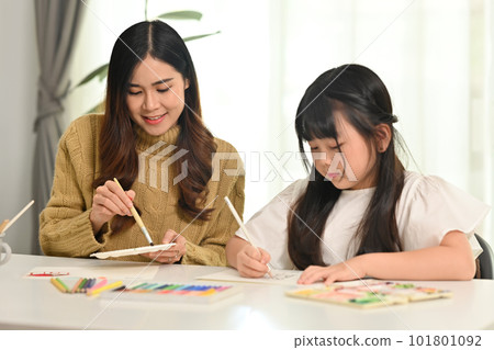 Mother and daughter drawing together in bright living room. Family home leisure concept Mother and daughter drawing together in bright living room. Family home leisure concept 101801092