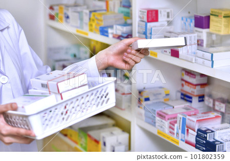 Pharmacist chemist woman standing refills the shelves with new stocks in pharmacy drugstore Pharmacist chemist woman standing refills the shelves with new stocks in pharmacy drugstore 101802359