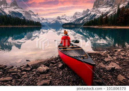 Scenery of Spirit Island with female traveler on kayak by the Maligne Lake in the sunset at Jasper national park 101806370