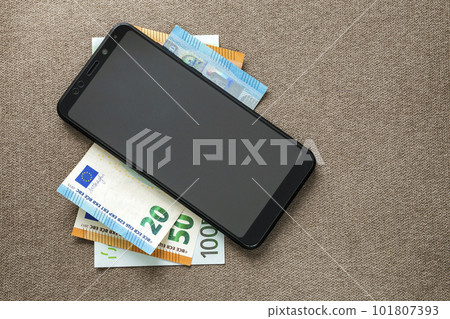New black modern digital cellphone on money euro banknotes on copy space texture background. Modern technology, communication and online trade using gadget concept. New black modern digital cellphone on money euro banknotes on copy space texture background. Modern technology, communication and online trade using gadget concept. 101807393