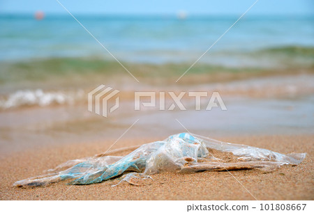 Left behind plastic bag garbage on sandy beach. Empty used dirty litter on sea shore. Environmental pollution. Ecological problem 101808667